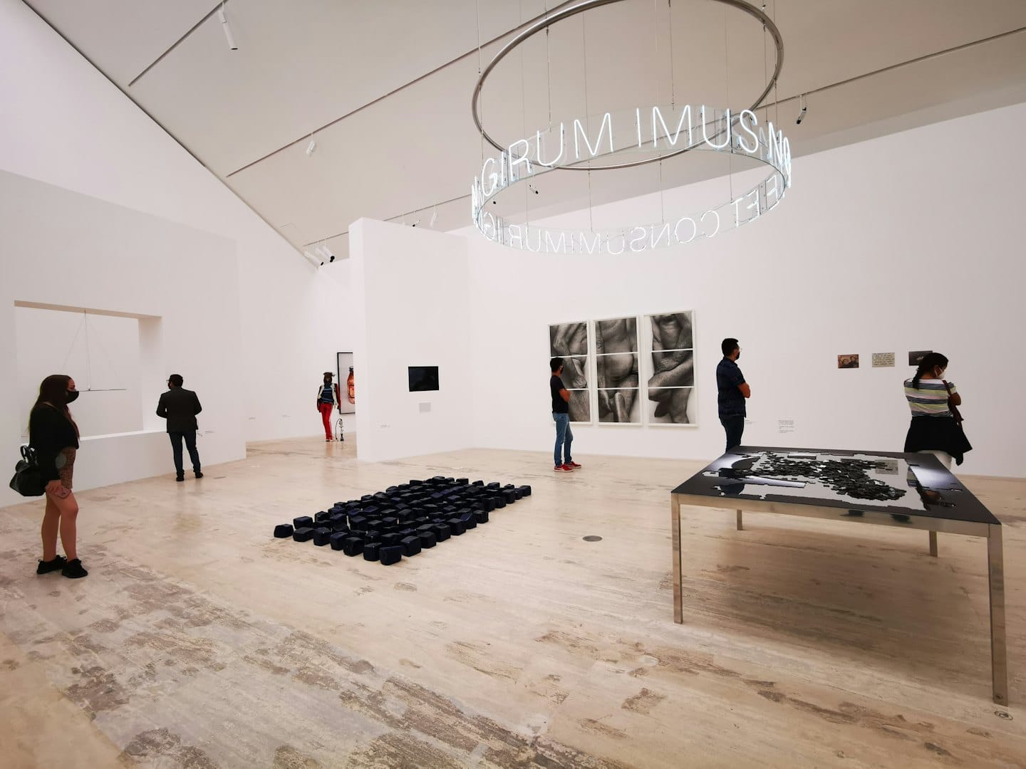 Bezoekers lopen door een galerie met hedendaagse kunst en sculpturen.