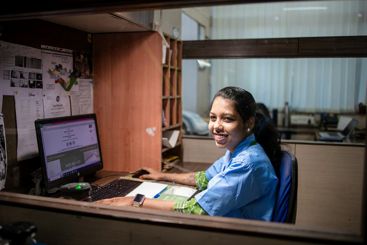 Vrouw in blauw uniform werkt aan haar kantoorcomputer.